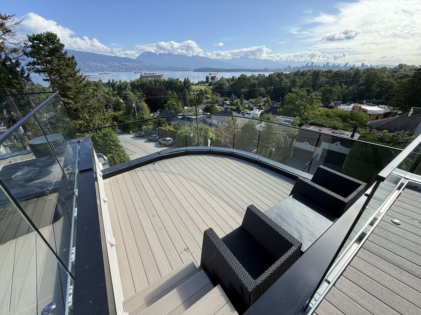 The curved lower deck, its frameless glass guard following the radius, with downtown Vancouver and the North Shore beyond.