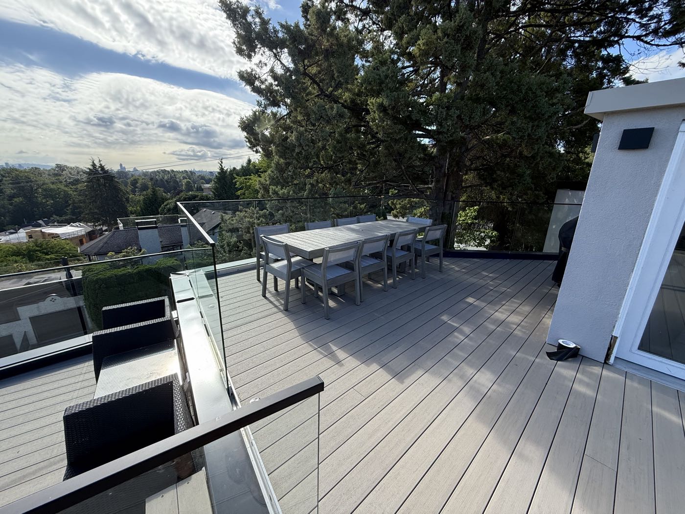 The upper deck laid out as a dining area, glass guard along the edge, looking east toward the city over the treetops.