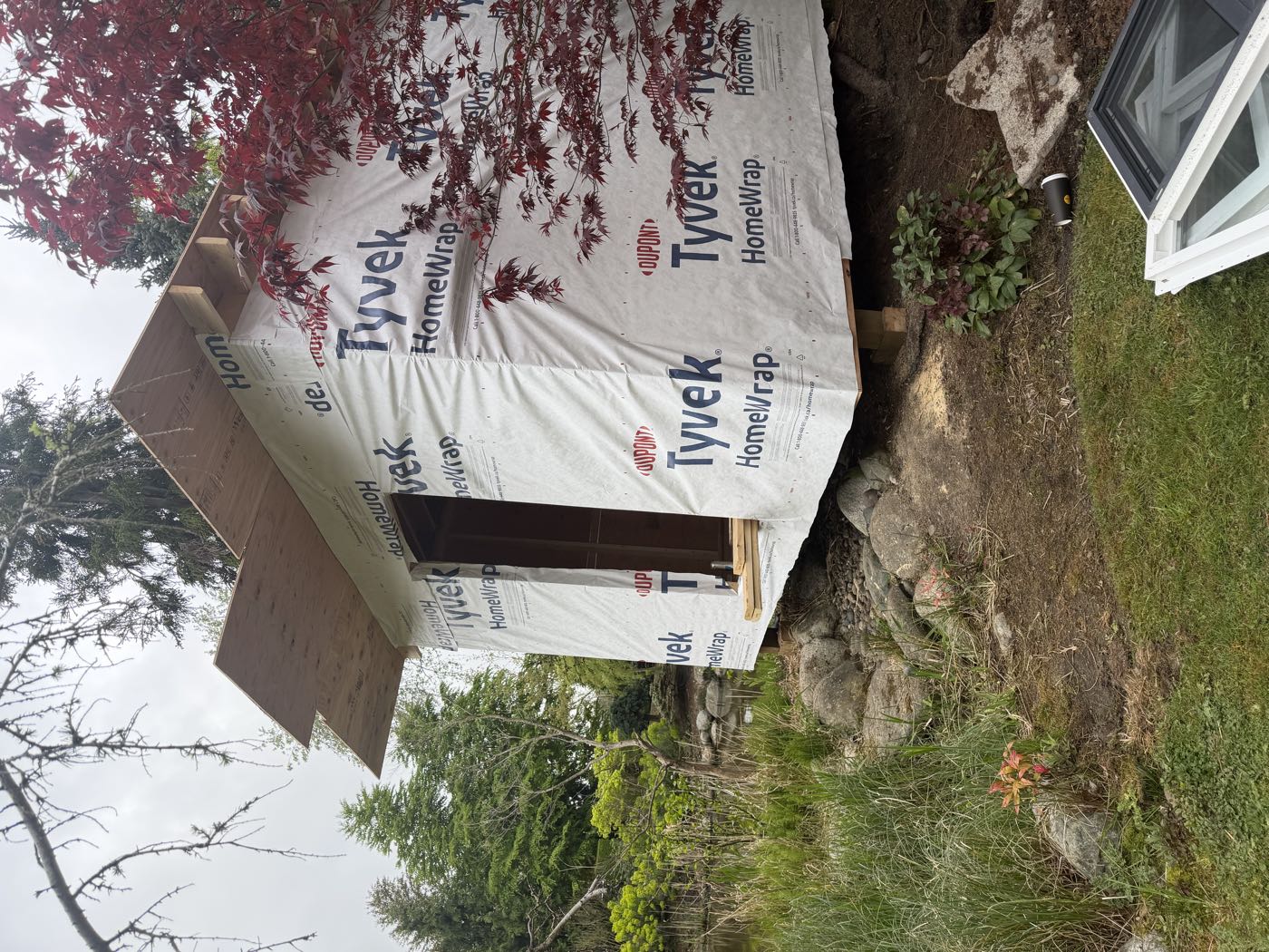 The finished shell wrapped in DuPont Tyvek HomeWrap, showing the deep roof overhang built to throw rain clear of the wall.